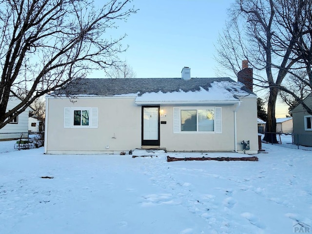 view of front of property featuring a chimney, fence, and stucco siding