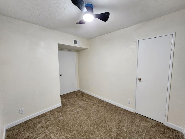 carpeted empty room featuring a ceiling fan, visible vents, a textured ceiling, and baseboards