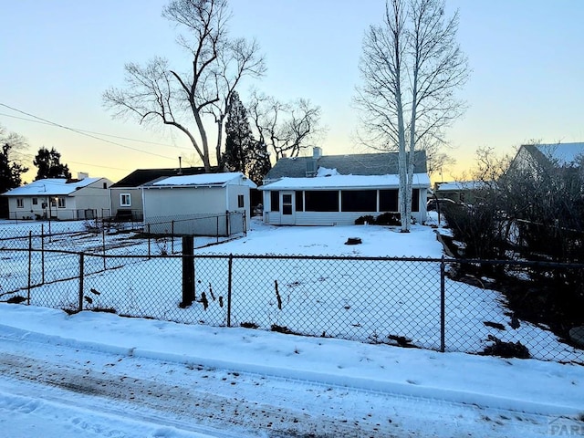 snow covered house with fence and a sunroom