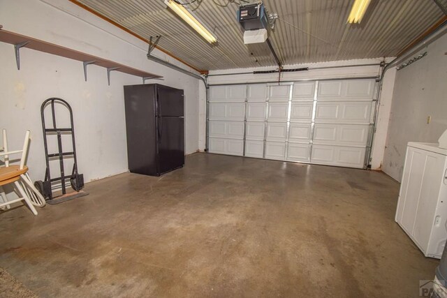 garage with a garage door opener, freestanding refrigerator, and washer / clothes dryer