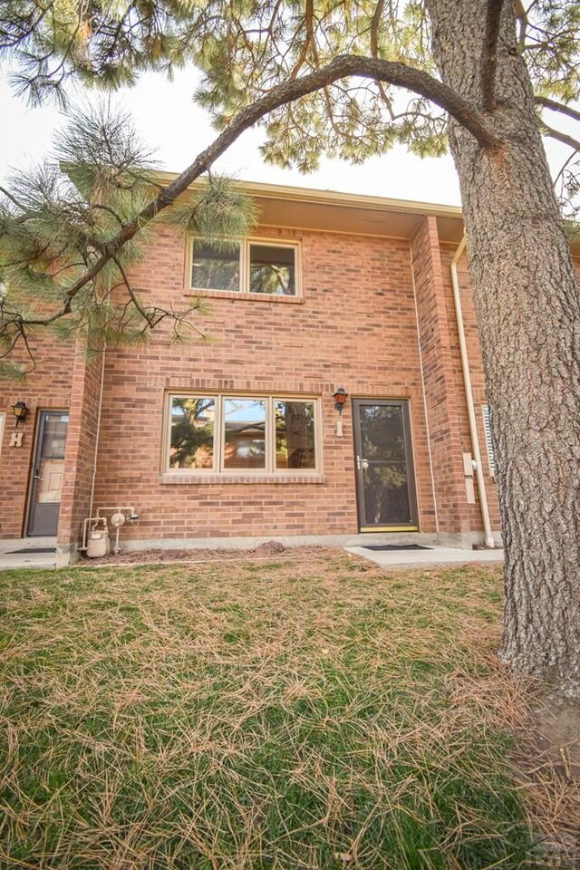 back of house with a yard and brick siding