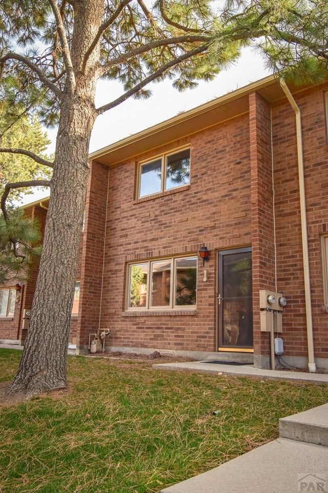 exterior space featuring brick siding and a front yard