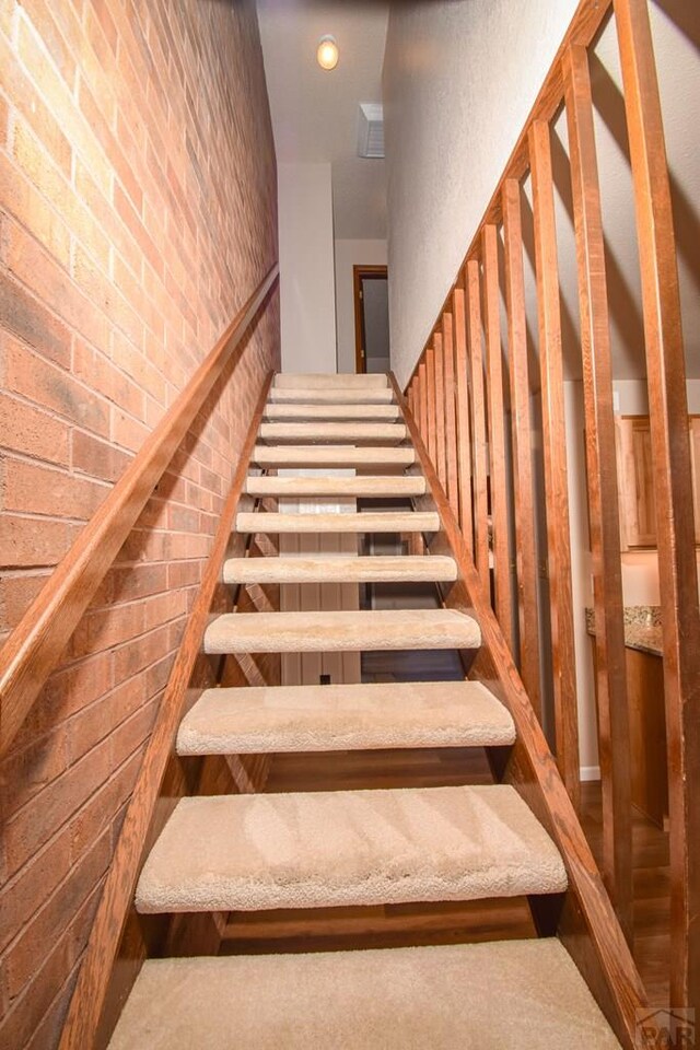 staircase featuring brick wall