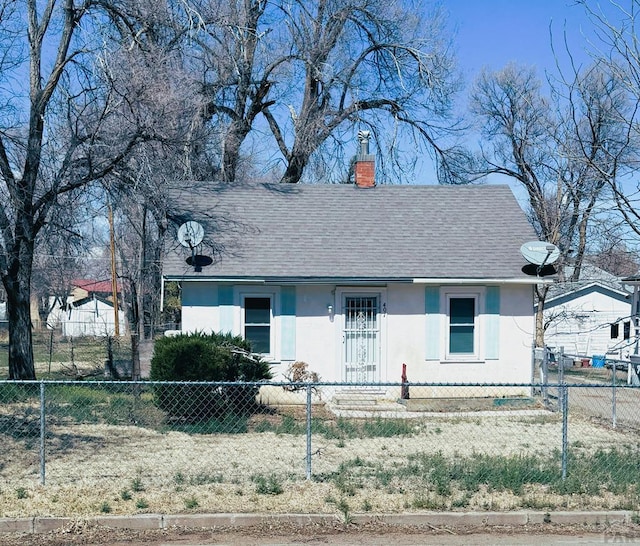 bungalow with a fenced front yard, a chimney, roof with shingles, and stucco siding