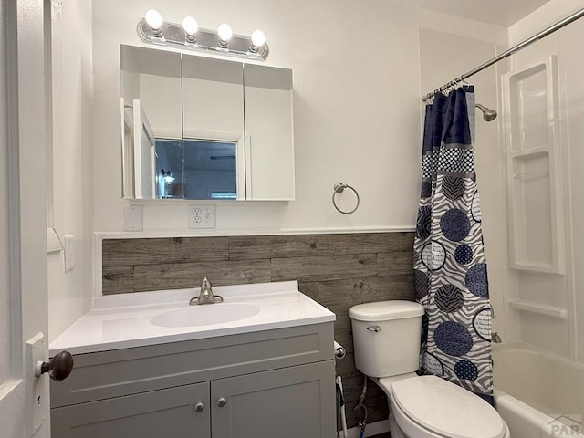 full bath featuring toilet, shower / bath combo with shower curtain, vanity, and wainscoting