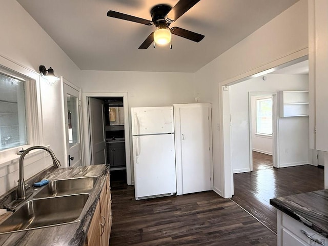 kitchen with dark wood-style floors, freestanding refrigerator, dark countertops, ceiling fan, and a sink