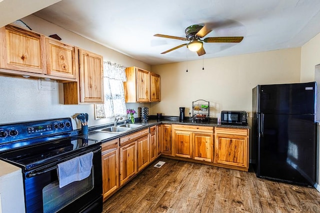 kitchen featuring ceiling fan, a sink, dark wood-type flooring, black appliances, and dark countertops