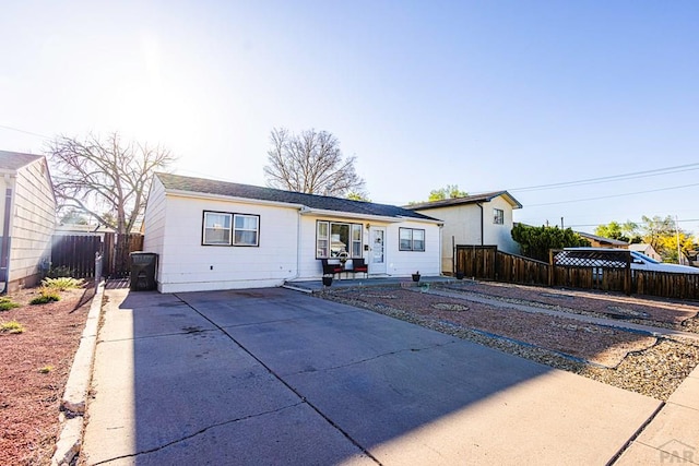rear view of property with concrete driveway and fence