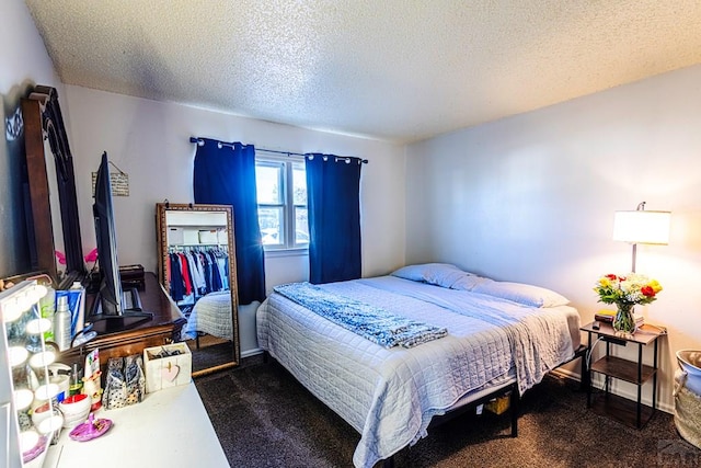bedroom with a textured ceiling and dark colored carpet