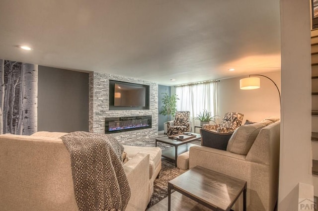 living room featuring a glass covered fireplace, recessed lighting, and wood finished floors