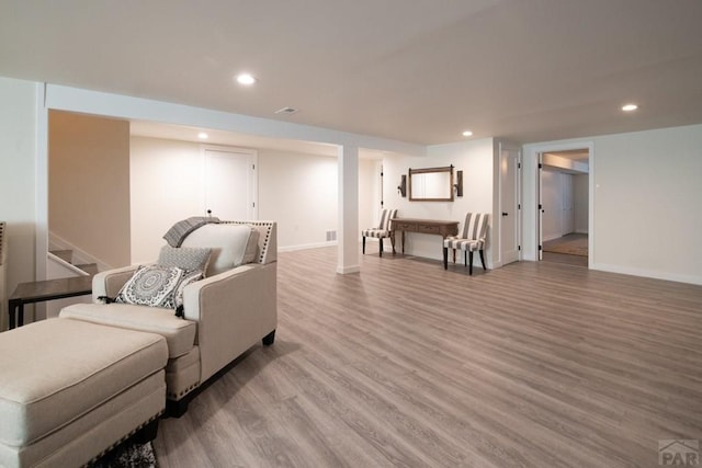 living room with light wood finished floors, baseboards, recessed lighting, and stairway