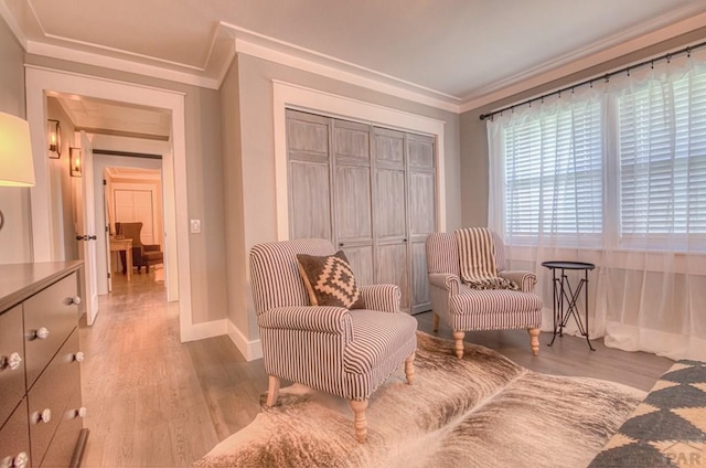 living area featuring baseboards, ornamental molding, and light wood finished floors