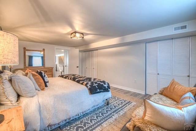 bedroom featuring baseboards, visible vents, and wood finished floors