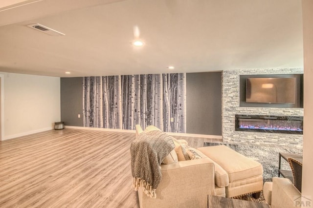 interior space featuring recessed lighting, baseboards, visible vents, a fireplace, and wood finished floors