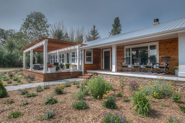 rear view of property featuring metal roof, covered porch, and a pergola