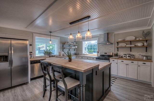 kitchen featuring open shelves, white cabinetry, appliances with stainless steel finishes, butcher block counters, and wall chimney range hood
