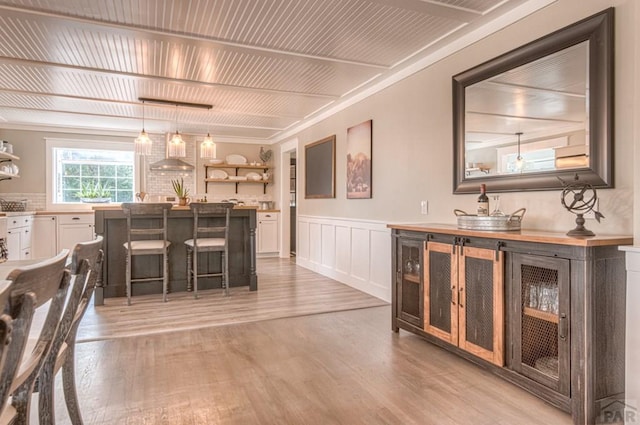 dining room featuring a wainscoted wall, light wood-style floors, and a decorative wall