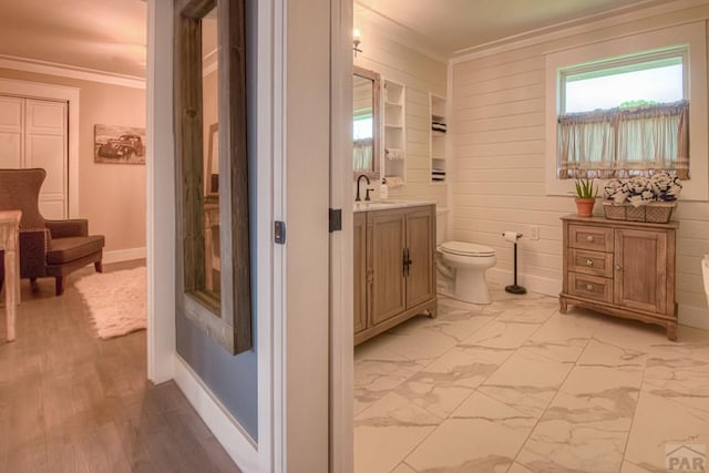 bathroom featuring vanity, crown molding, toilet, baseboards, and marble finish floor