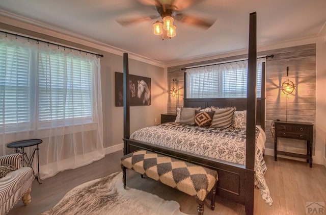 bedroom featuring ornamental molding, wood finished floors, multiple windows, and ceiling fan