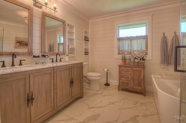 full bath featuring marble finish floor, a freestanding bath, ornamental molding, and a sink