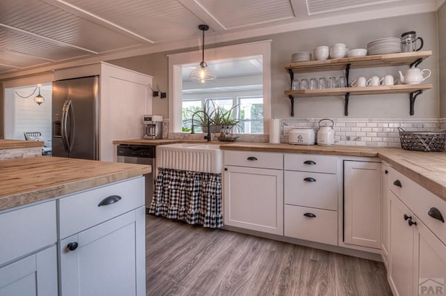 kitchen featuring white cabinets, wood counters, appliances with stainless steel finishes, and light wood-style floors