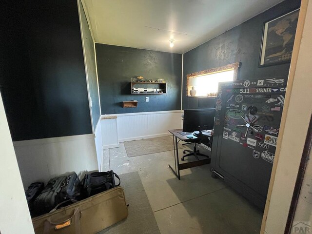 miscellaneous room with concrete flooring and wainscoting