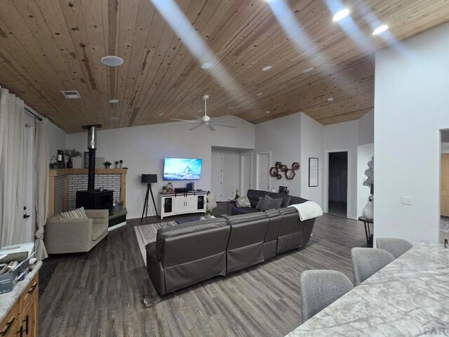 living room featuring ceiling fan, recessed lighting, dark wood-type flooring, wood ceiling, and a wood stove