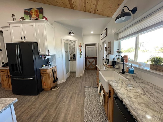 kitchen with black appliances, brown cabinetry, a sink, and white cabinets