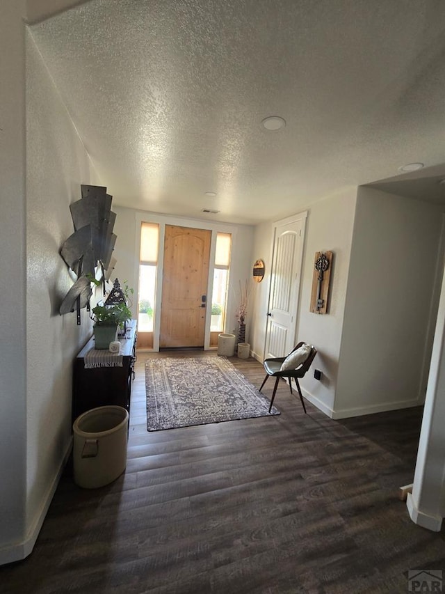 foyer featuring dark wood-style floors, a textured ceiling, and baseboards