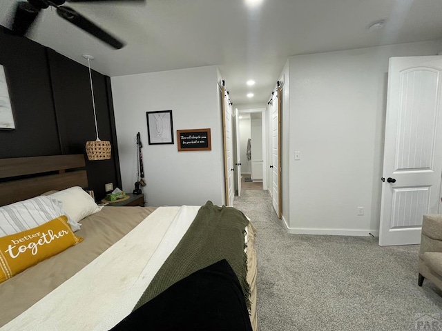 bedroom featuring recessed lighting, a barn door, baseboards, and light colored carpet