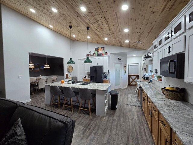 kitchen with glass insert cabinets, white cabinetry, brown cabinets, black appliances, and decorative light fixtures