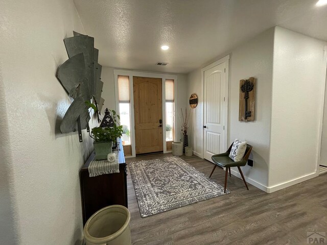 entryway featuring visible vents, a textured ceiling, baseboards, and wood finished floors