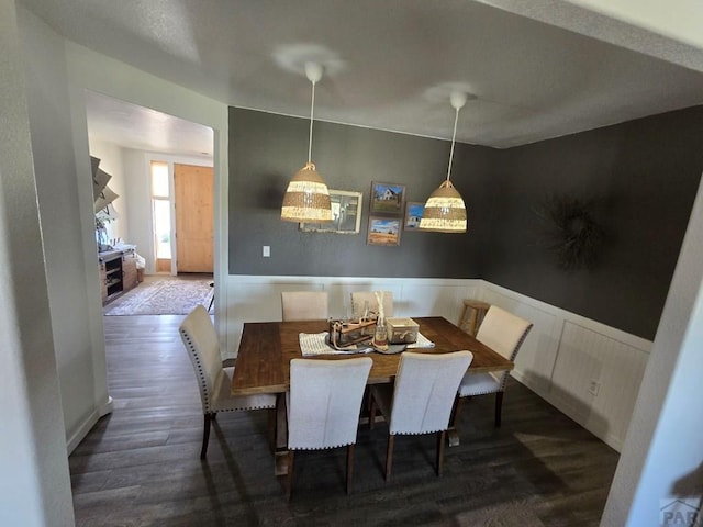 dining room with dark wood-type flooring and wainscoting