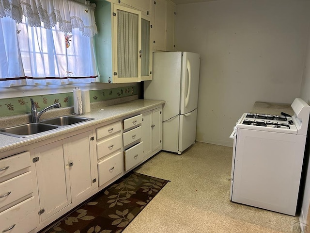 kitchen with white appliances, light countertops, a sink, and white cabinetry