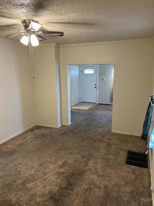 carpeted spare room with baseboards, a textured ceiling, visible vents, and crown molding