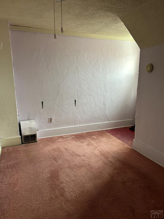 carpeted spare room with a textured ceiling, a textured wall, visible vents, and baseboards