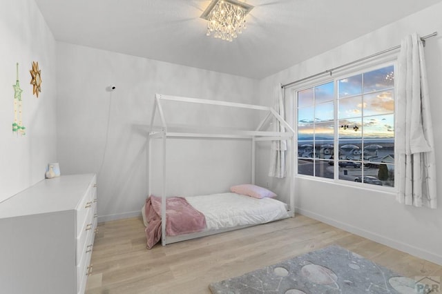 2200 Meadowlark Ln, Pueblo, CO 81008 - bedroom with light wood-type flooring, baseboards, and an inviting chandelier