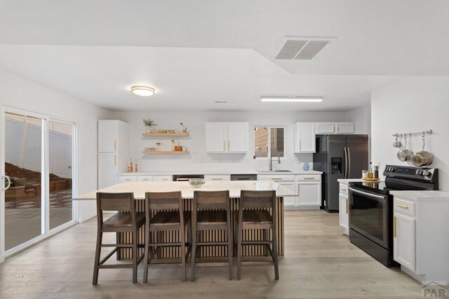 2200 Meadowlark Ln, Pueblo, CO 81008 - kitchen featuring open shelves, a sink, black appliances, a breakfast bar, and visible vents