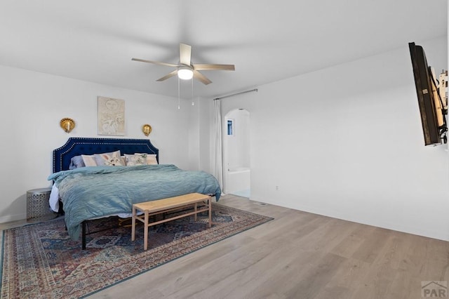 2200 Meadowlark Ln, Pueblo, CO 81008 - bedroom featuring connected bathroom, arched walkways, a ceiling fan, and wood finished floors