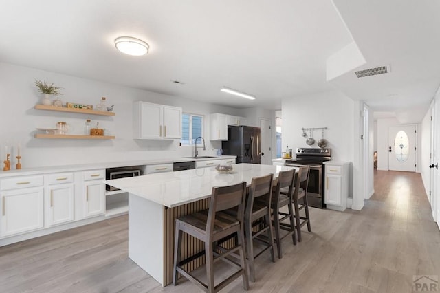 2200 Meadowlark Ln, Pueblo, CO 81008 - kitchen with fridge with ice dispenser, visible vents, a sink, a kitchen bar, and stainless steel electric range oven