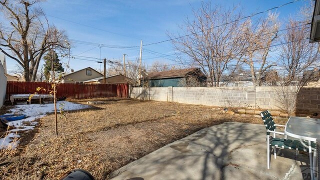 snowy yard featuring a patio area and a fenced backyard