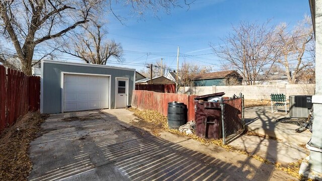 detached garage featuring driveway, cooling unit, and fence