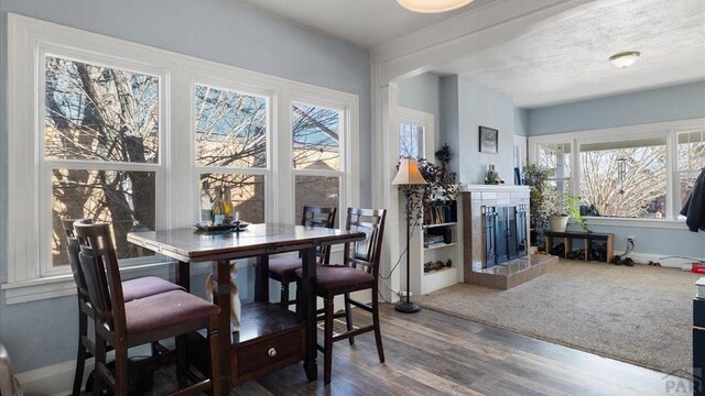 dining room featuring a tiled fireplace and wood finished floors