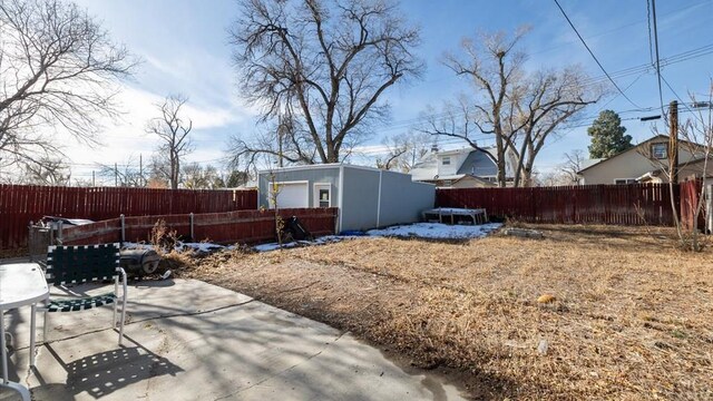 view of yard with a patio area, a fenced backyard, and an outbuilding