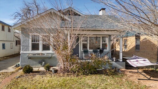 rear view of property featuring a shingled roof and a chimney