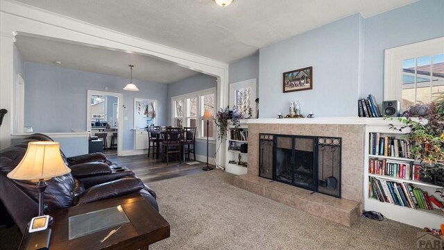 carpeted living area featuring a tile fireplace