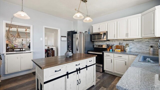 kitchen with stainless steel appliances, white cabinets, decorative backsplash, dark stone countertops, and pendant lighting