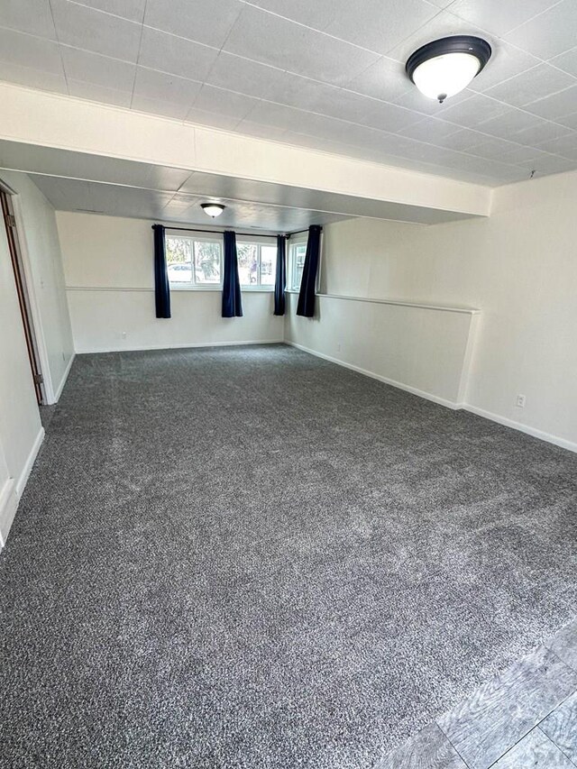 basement featuring dark carpet and baseboards