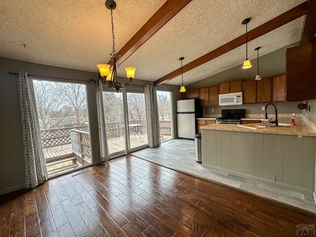 kitchen featuring range with electric stovetop, tile countertops, wood-type flooring, white microwave, and freestanding refrigerator