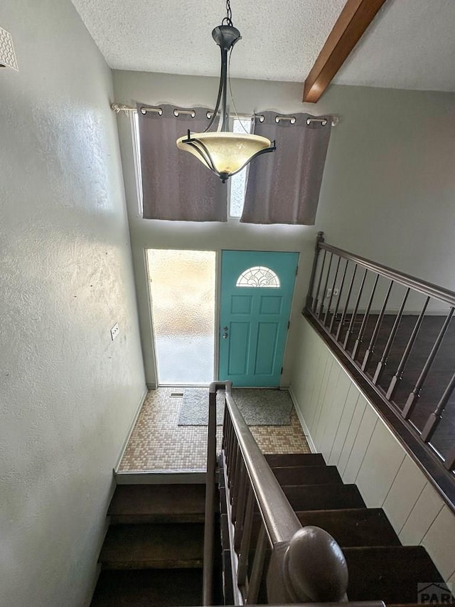 staircase with a textured ceiling and beamed ceiling